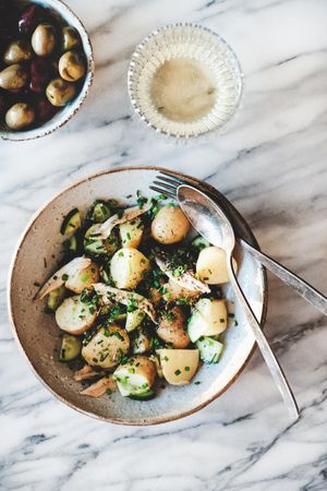 Greek style potato salad, olive bowl and wine, top view, close up