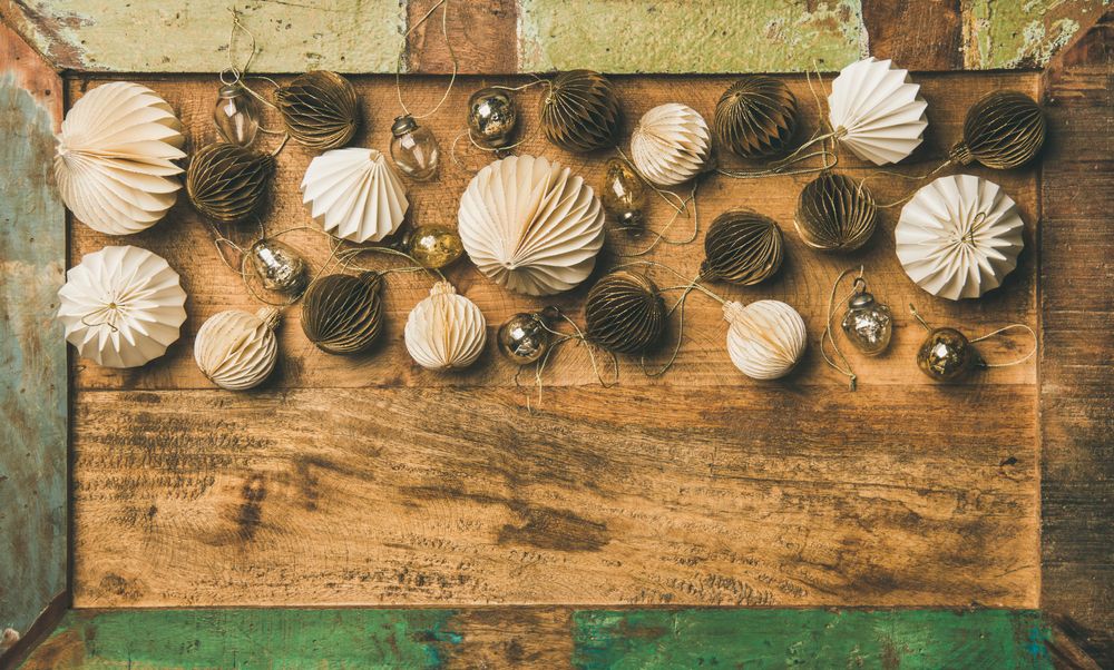 Gold and cream folded tree ornaments, and baubles on wooden counter, copy space