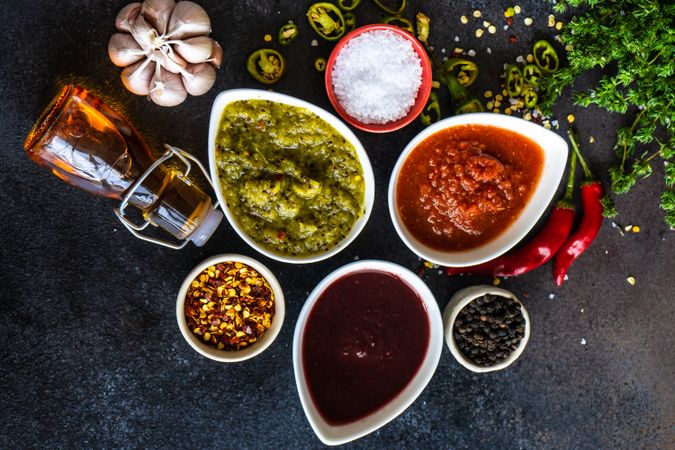 Top view of variety of traditional Georgian satsebeli sauces with kiwi, tomato and berried on stone background