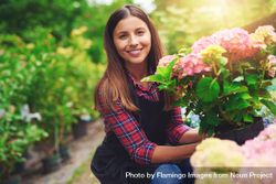 Smiling florist pictured with colorful flowers in a greenhouse 56nVV5