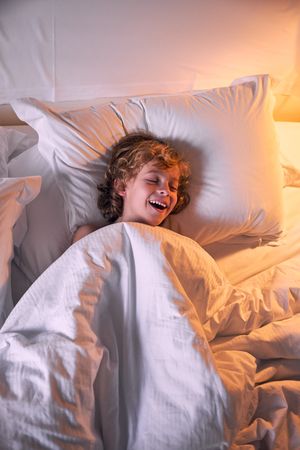 Happy boy with closed eyes in bed