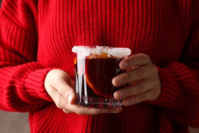 Girl in red sweater holding glass with mulled wine, close up