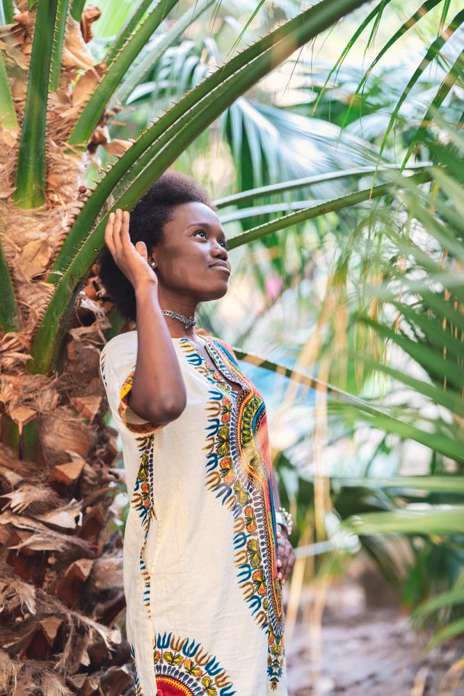 Cheerful Black woman amidst palm leaves