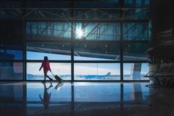 Anonymous female with luggage walking in empty airport