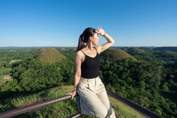 Happy woman standing on observation deck on hill