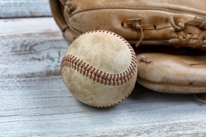 Close up of a used baseball and mitt on vintage wood