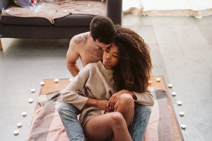 Multiethnic couple hugging on floor at home