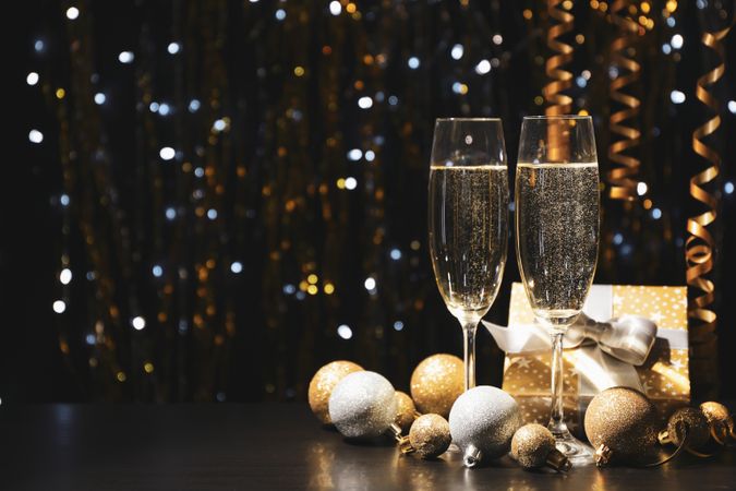 Christmas baubles and champagne glasses on blurred background, copy space