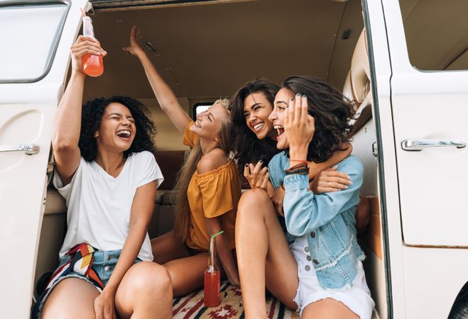 Friends in van raising hands and laughing