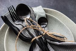 Table setting with dark cutlery & string on concrete background