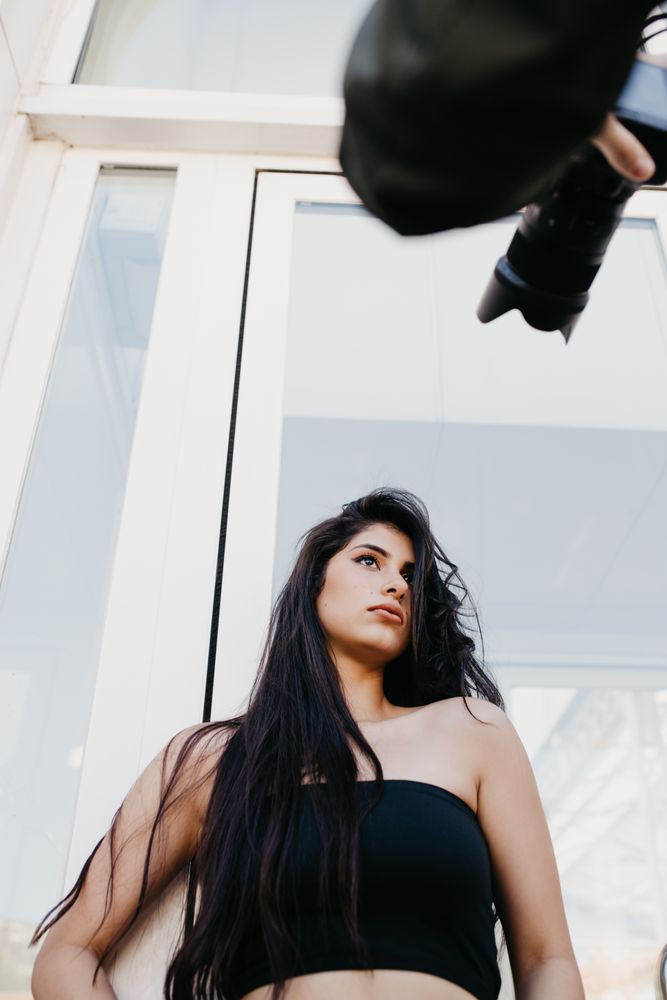 Crop photographer taking pictures of young model