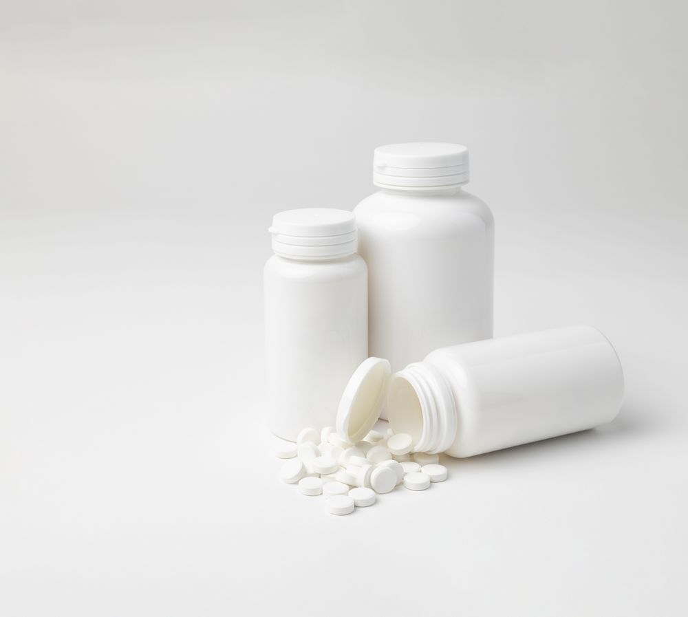 Mockup of a aspirin bottles, different sizes, one lying down open, with copyspace