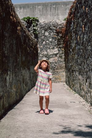 Girl in narrow stone walkway looking up
