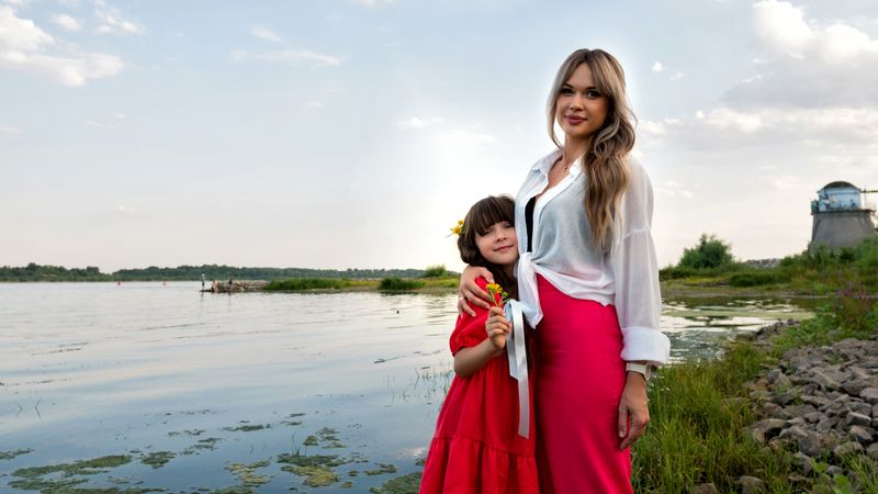 Mom and little daughter walking by the lake or pond