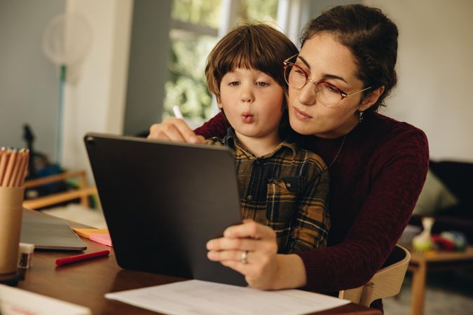 Mother teaching son how to write on digital tablet