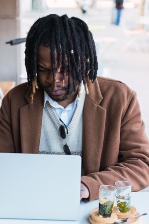 Black man browsing on laptop on restaurant terrace