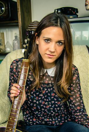 Young hipster female with acoustic guitar at home