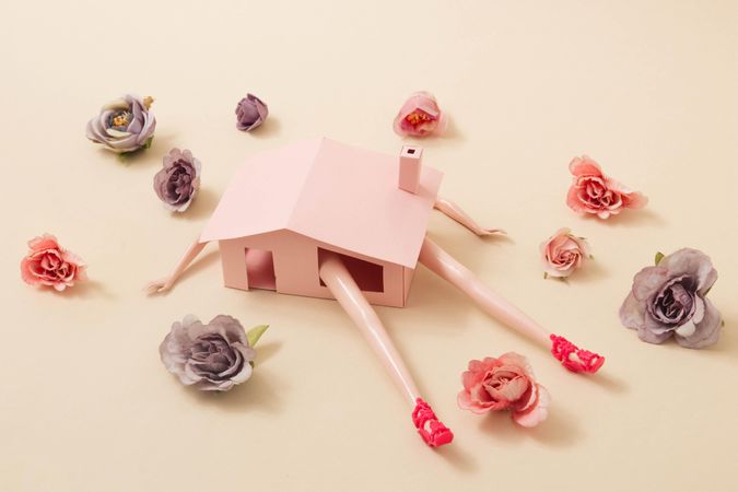 Spring flowers and leaves around pink house with doll limbs protruding