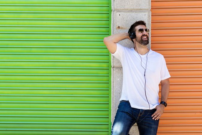 Man in headphones leaning on wall between colorful shutters