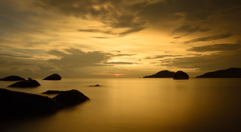 Silhouette of rocks on water during golden hour