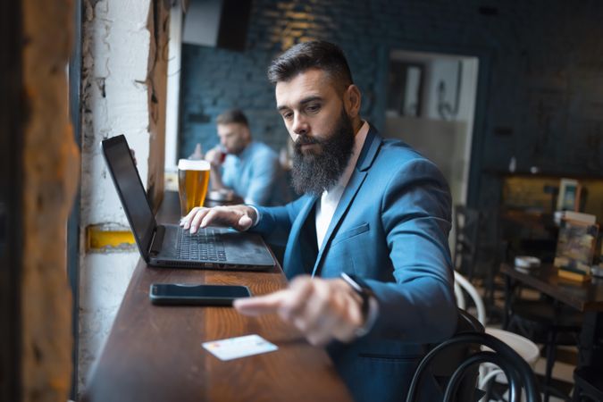 Man with laptop and beer in a pub