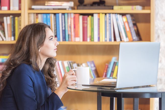 Woman having coffee in front of a laptop