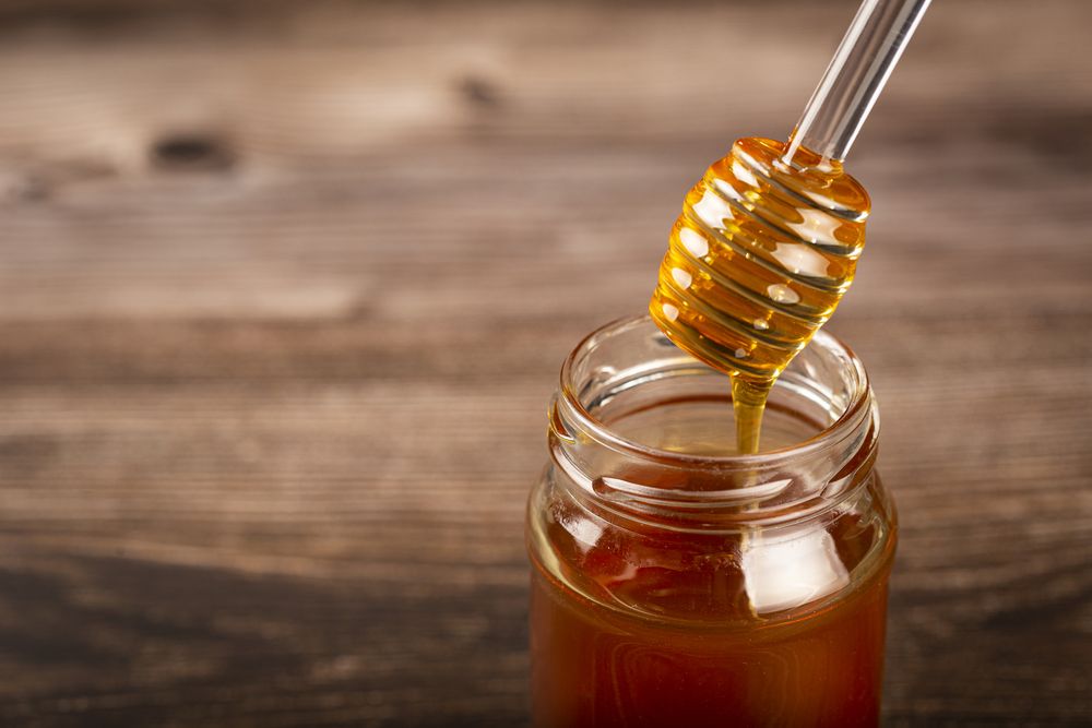 Honey in glass jar on the table.