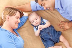 Young  Couple Laying With Their Infant On A Blanket