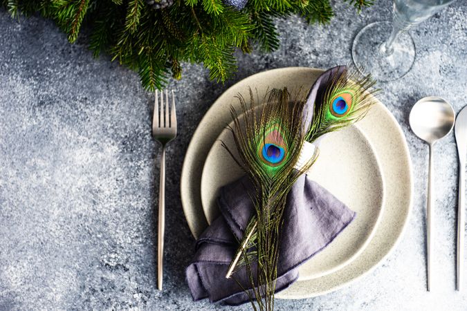 Elegant festive table setting for Christmas dinner with peacock feathers