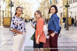 Three women looking back standing in shopping area bEq1Gb