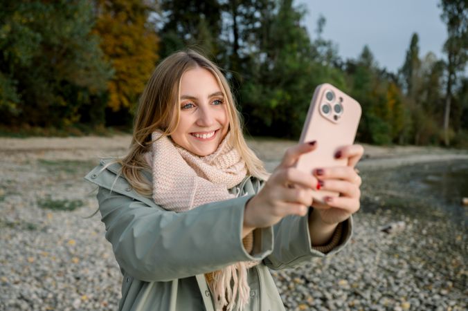 portrait of young woman taking selfie at lake