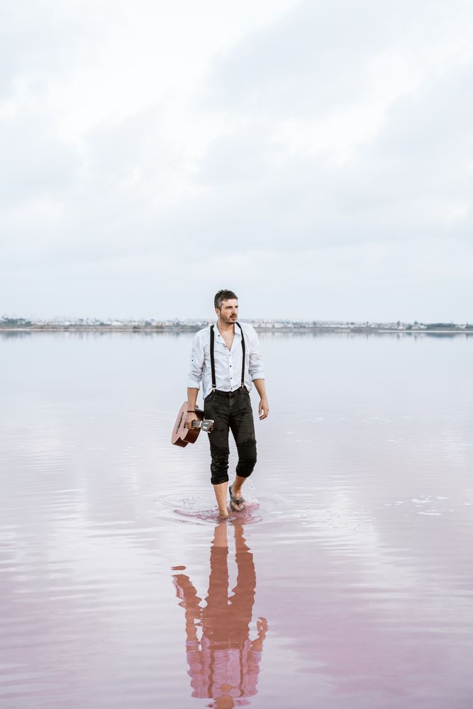 Musician holding guitar at seaside