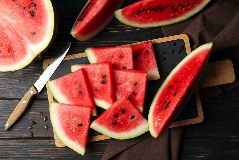 Composition with board with watermelon slices on wooden table
