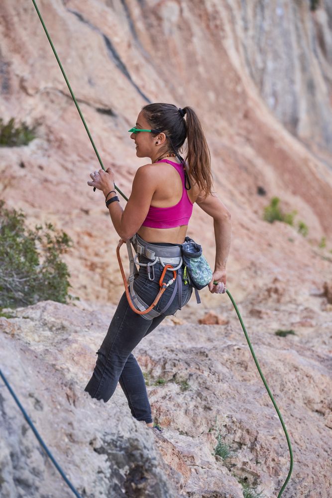 Female climber hanging on rope in mount