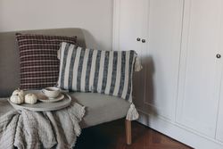 Cup of coffee, tea on round serving tray, little pumpkins, breakfast on linen sofa, checkered, striped cushions