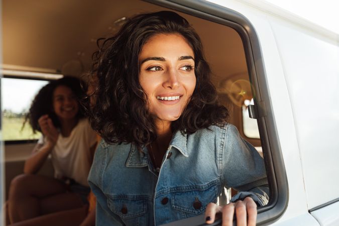Curly haired woman looking out of van door