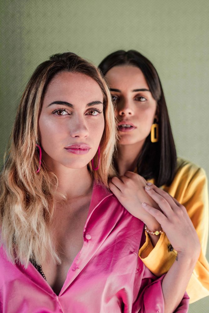 Young trendy women in bright clothes looking at camera