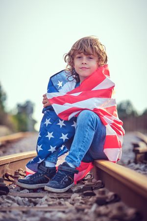 Kid wrapped in USA flag on railway