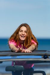 Smiling woman leaning on roof of car