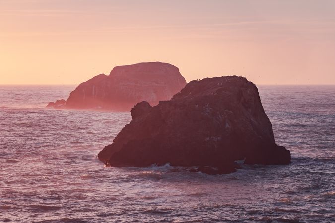 Two large rocks in the Pacific Ocean in late afternoon
