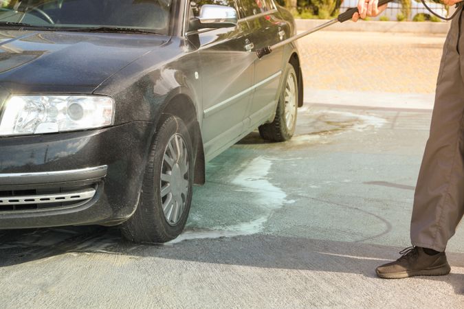 A man washes a car in a manual car wash. Clear car