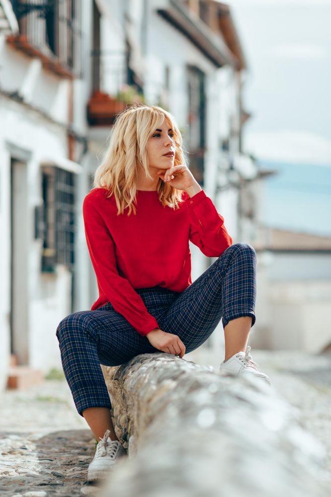 Blonde female with red shirt sitting outdoors, vertical