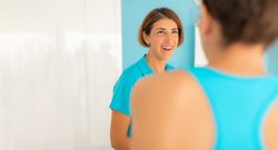 A woman, a physiotherapist, smiles as she chats animatedly with one of her patients at the clinic