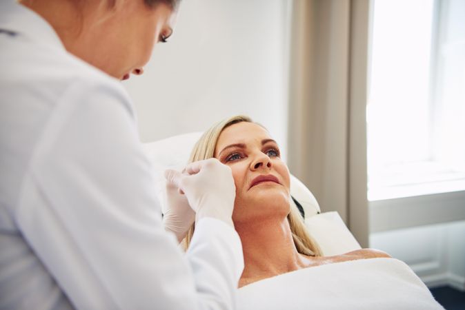 Dermatologist performing treatment on a mature patient’s face