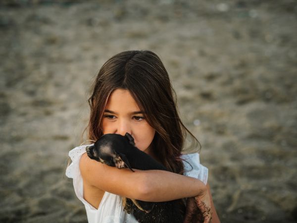 Girl with little dog on sandy beach