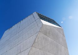 Looking up at vents on grey building against a blue sky