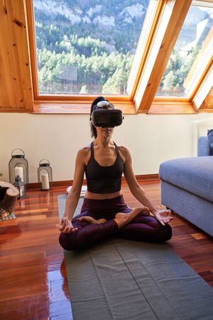 Fit female in virtual reality glasses doing Lotus yoga pose