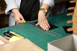Hands of woman using sharp knife when cutting paper for making notebook