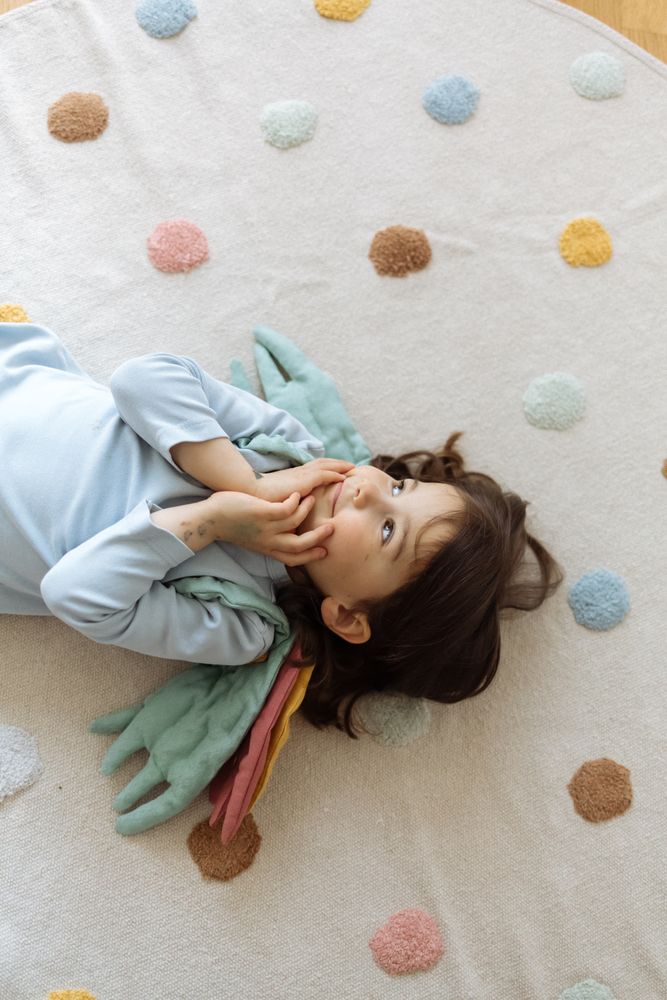 Little girl with angelic wings lying with back on floor