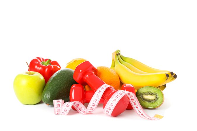 Dumbbells, measuring tape and fruits isolated on plain background